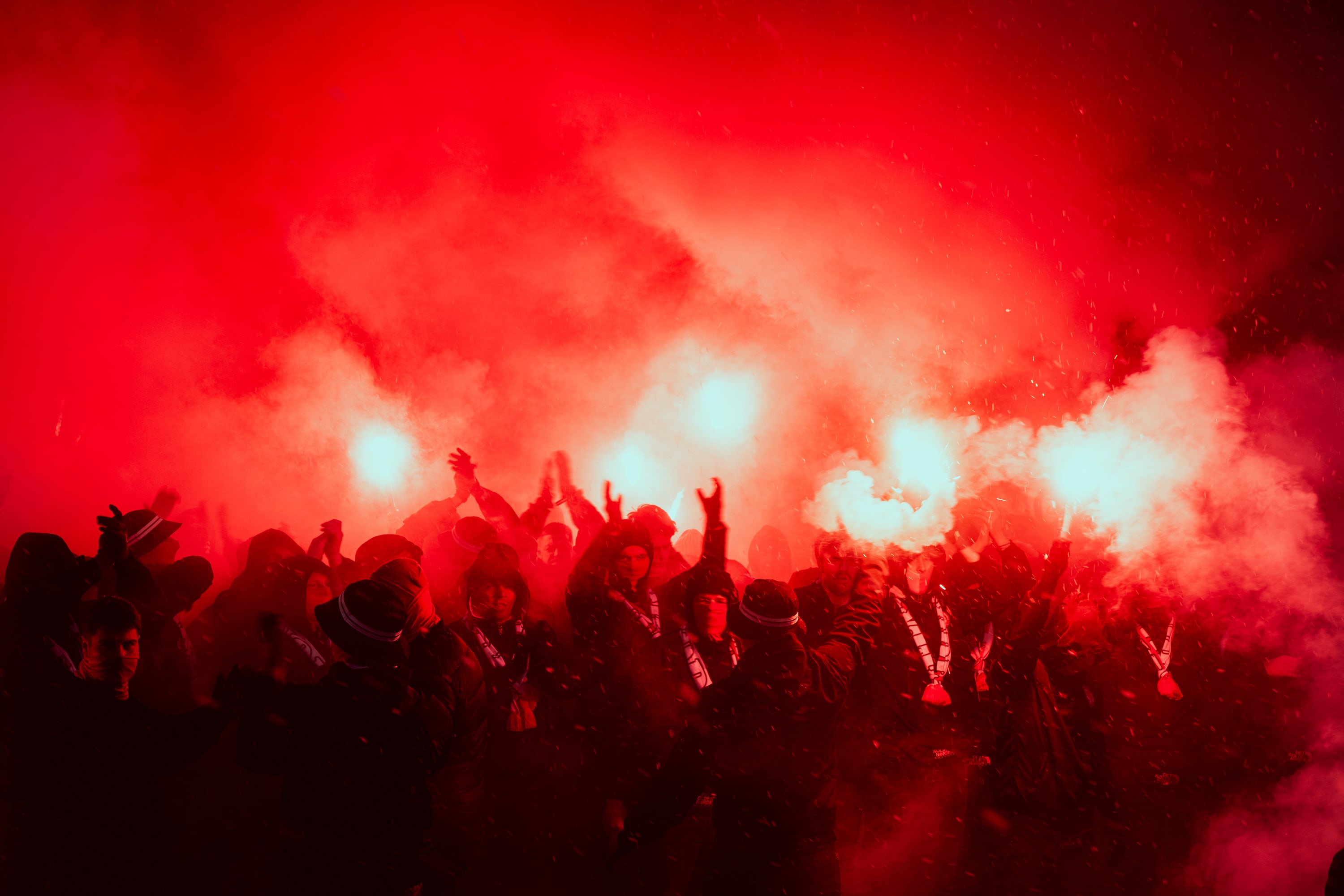 Supporters gather beneath burning red flares and drifting smoke