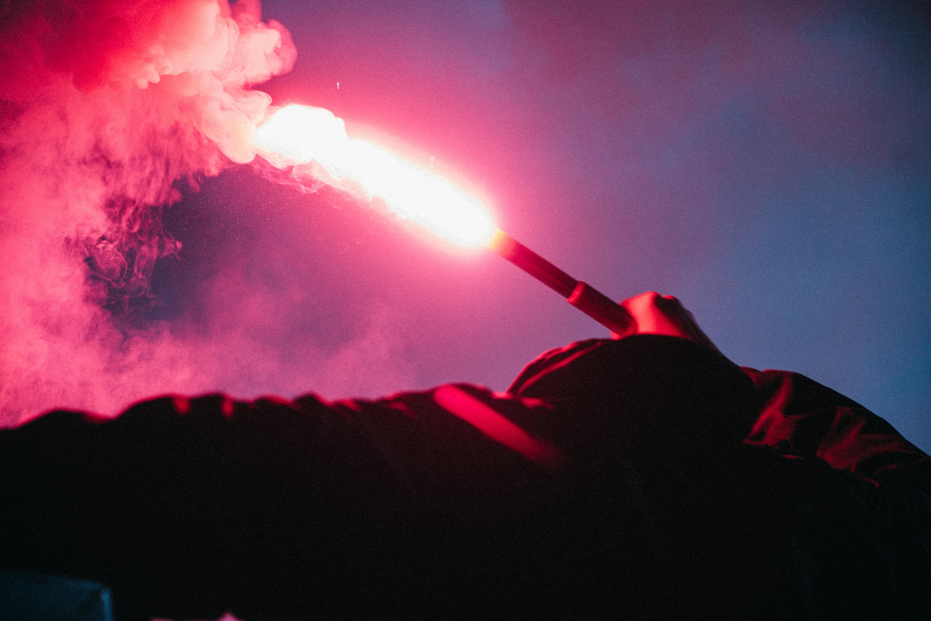 Close view of a burning red flare held against a blue night sky